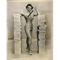 1955 Press Photo Model Stands In Between The Stacks Of Film - nef69346