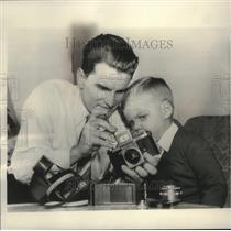 1953 Press Photo John Noble And Nephew Work On Camera At Home In Detroit