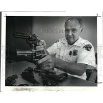 1987 Press Photo Lt. Walter Galyin holds up a 357 Mg. and a pellet gun