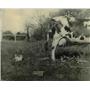 1935 Press Photo Taking precaution a farmer ties the cow's tail to a bucket.